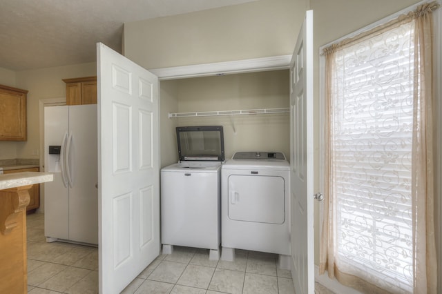 laundry room featuring a wealth of natural light, washing machine and dryer, and light tile patterned floors