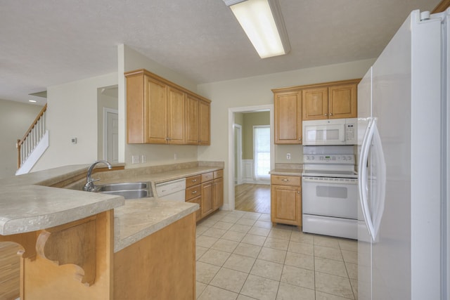 kitchen featuring light hardwood / wood-style flooring, kitchen peninsula, sink, a kitchen breakfast bar, and white appliances