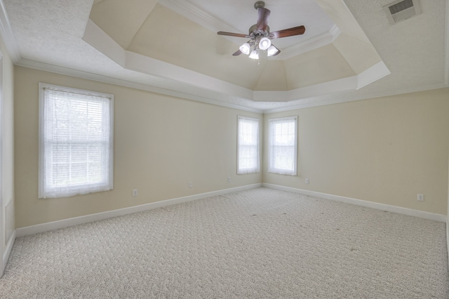 carpeted spare room with ceiling fan, a raised ceiling, and ornamental molding