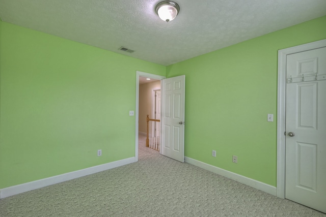 unfurnished bedroom with a closet, light colored carpet, and a textured ceiling