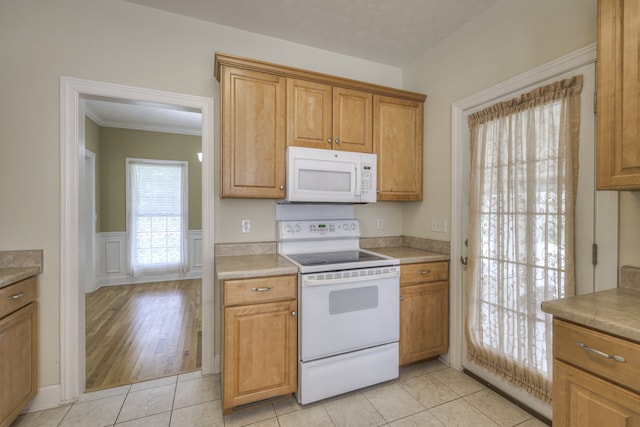 kitchen with ornamental molding, white appliances, and light tile patterned floors