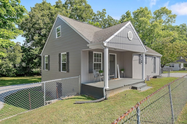 view of front of house with board and batten siding, roof with shingles, fence, and a front lawn