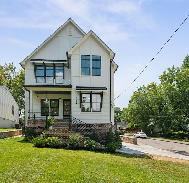 view of front of property with concrete driveway, a front lawn, a porch, board and batten siding, and brick siding