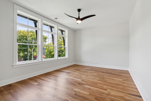 unfurnished room with visible vents, light wood finished floors, a ceiling fan, and baseboards