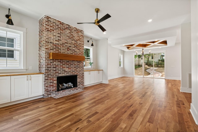 unfurnished living room featuring a brick fireplace, light wood-style flooring, and baseboards