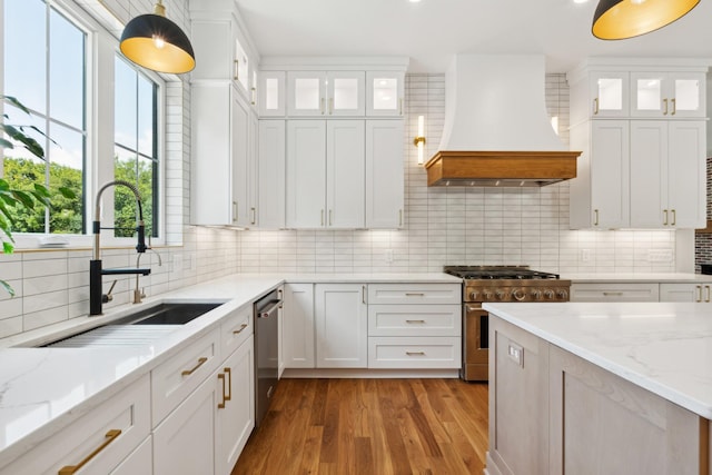 kitchen with glass insert cabinets, stainless steel appliances, custom range hood, and white cabinetry