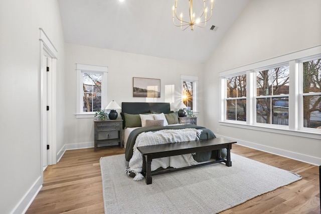 bedroom featuring high vaulted ceiling, light wood-style flooring, a notable chandelier, visible vents, and baseboards