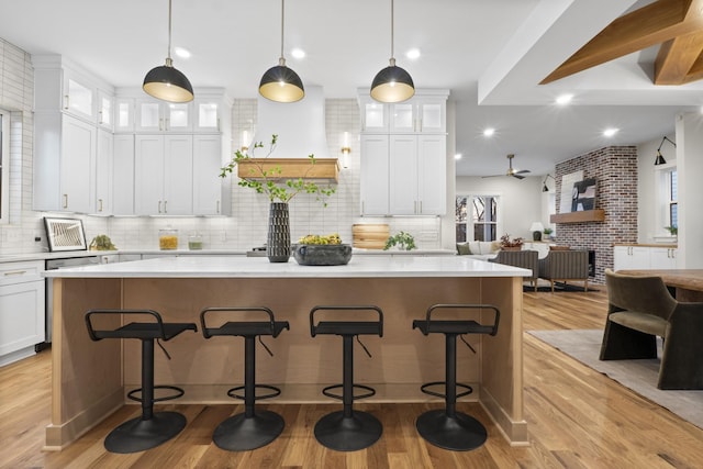 kitchen with glass insert cabinets, open floor plan, light countertops, and white cabinets