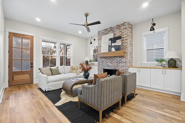 living room with a ceiling fan, a fireplace, light wood-style flooring, and recessed lighting