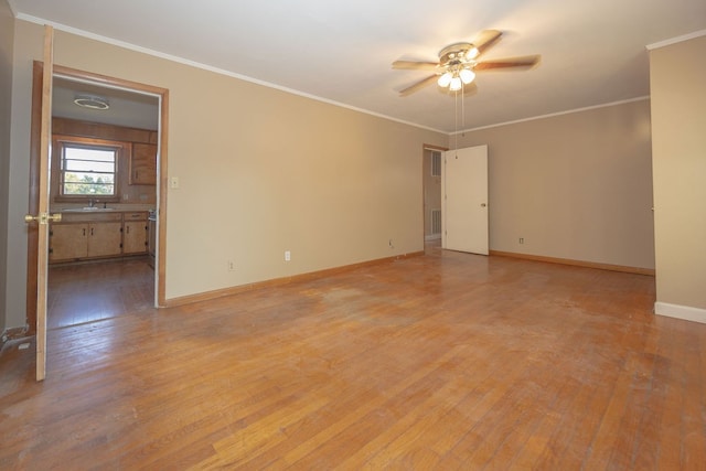 empty room featuring light hardwood / wood-style flooring, ceiling fan, ornamental molding, and sink