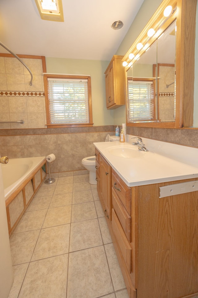 full bathroom with tile patterned floors, vanity, tiled shower / bath combo, tile walls, and toilet