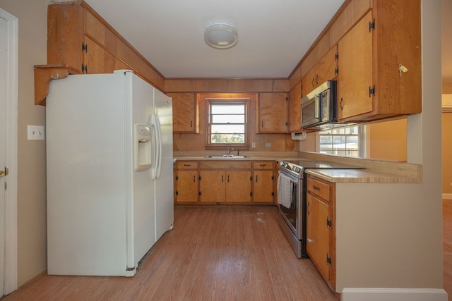 kitchen with stainless steel appliances, light hardwood / wood-style flooring, and sink