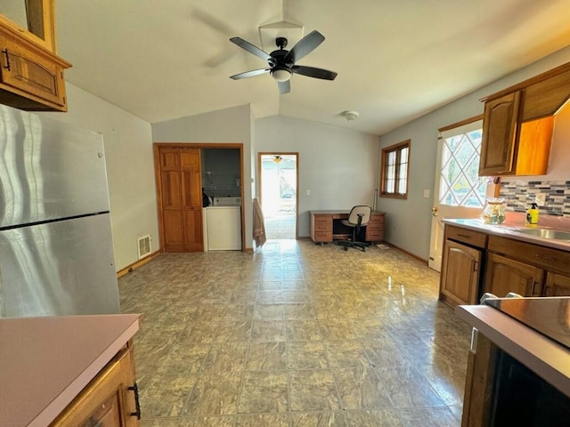 kitchen featuring ceiling fan, backsplash, washer / clothes dryer, stainless steel fridge, and lofted ceiling