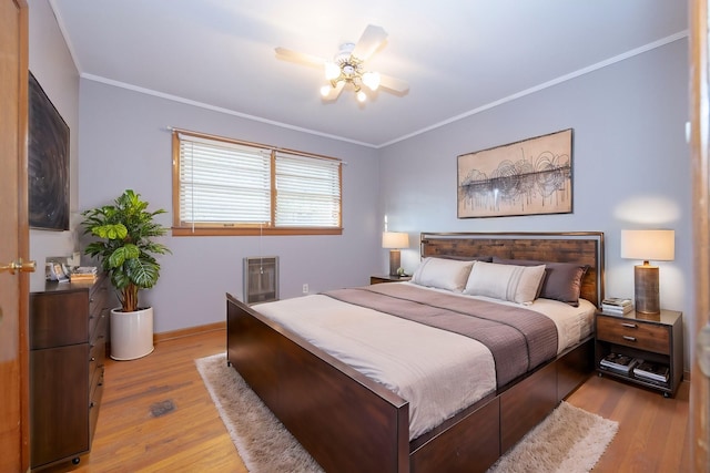 bedroom featuring heating unit, light hardwood / wood-style flooring, ceiling fan, and crown molding