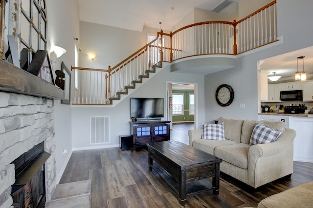 living room with a high ceiling, wood-type flooring, and a fireplace