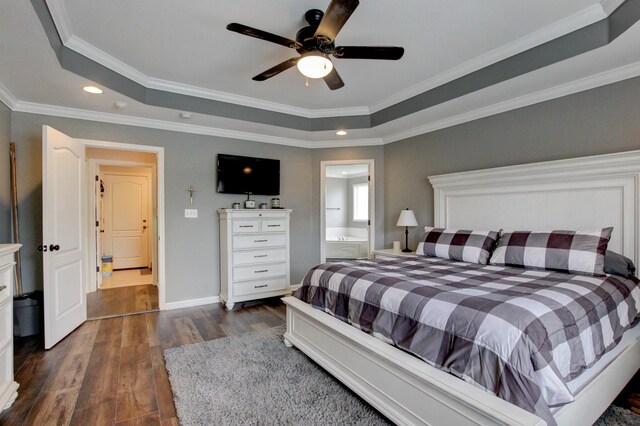 bedroom with ornamental molding, dark wood-type flooring, a tray ceiling, ceiling fan, and connected bathroom