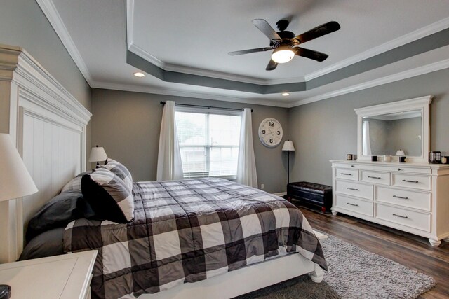 bedroom featuring a tray ceiling, ceiling fan, dark wood-type flooring, and ornamental molding