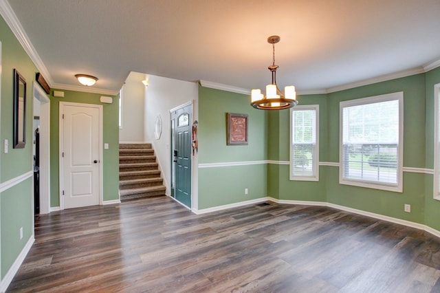 spare room with crown molding, dark wood-type flooring, and a notable chandelier