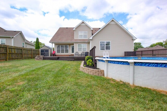 back of property featuring a lawn, a swimming pool side deck, and a shed