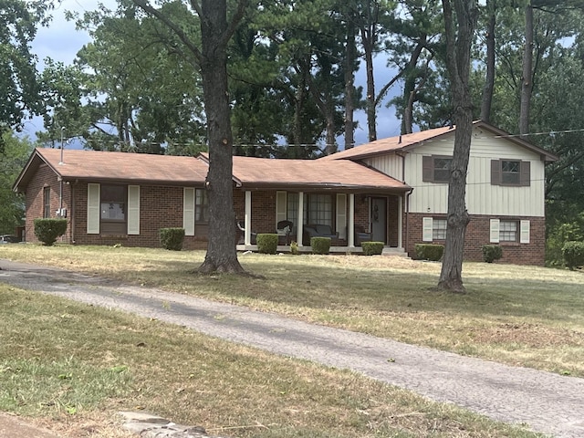 tri-level home with brick siding, a porch, and a front yard