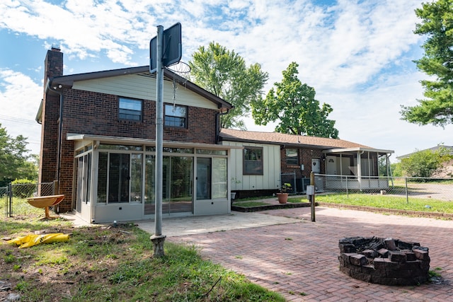 rear view of house featuring a fire pit, a sunroom, and a patio area