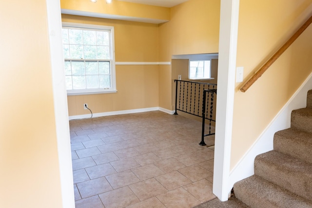 interior space featuring light tile patterned floors, stairs, and baseboards