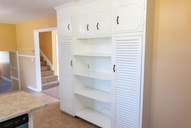 interior space with dishwashing machine, light tile patterned floors, light stone countertops, open shelves, and white cabinetry