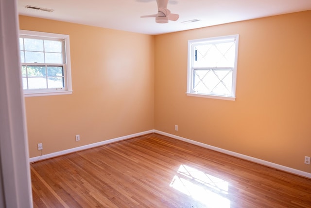 unfurnished room with ceiling fan, visible vents, baseboards, and wood finished floors