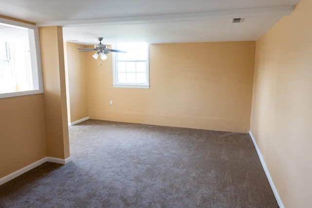 spare room with dark colored carpet, visible vents, baseboards, and ceiling fan