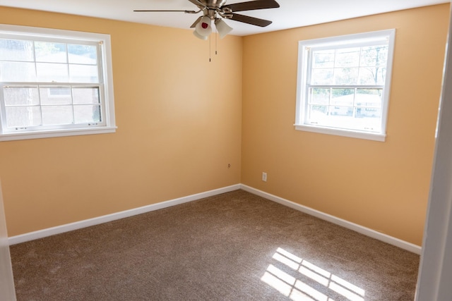 carpeted empty room featuring a wealth of natural light, baseboards, and a ceiling fan