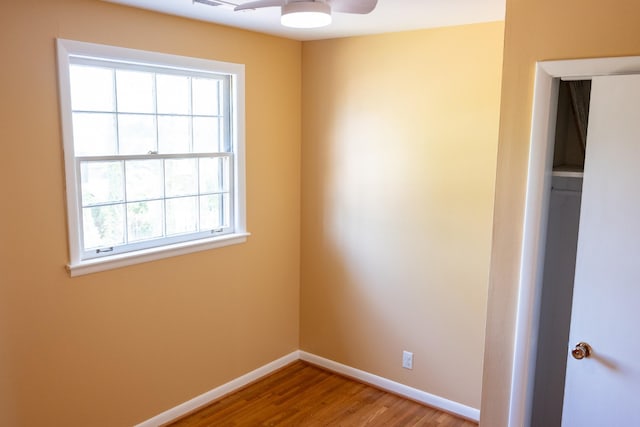 empty room featuring baseboards, wood finished floors, and a ceiling fan