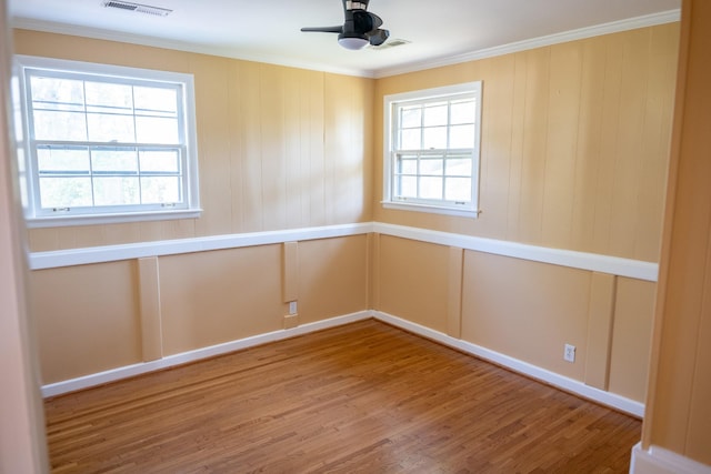 empty room with a healthy amount of sunlight, crown molding, a ceiling fan, and wood finished floors