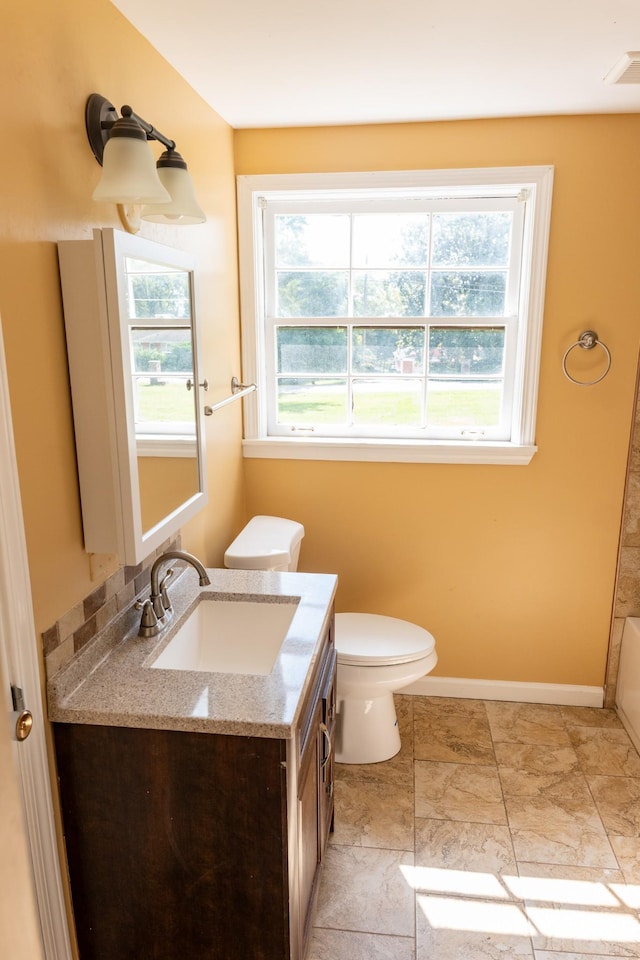 full bathroom featuring visible vents, toilet, a tub to relax in, baseboards, and vanity