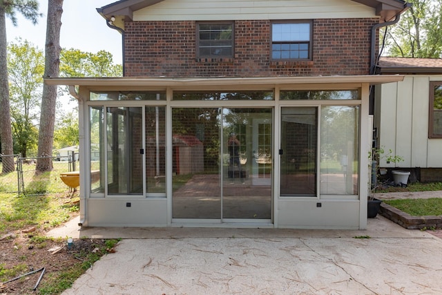 entrance to property featuring brick siding, a patio area, and fence