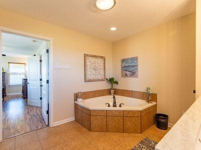 bathroom with a garden tub, tile patterned flooring, and baseboards