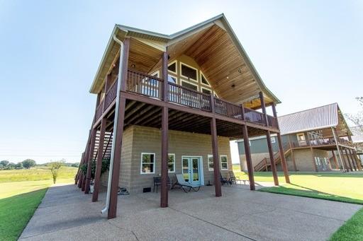 back of property with a lawn, french doors, stairway, a wooden deck, and a patio area