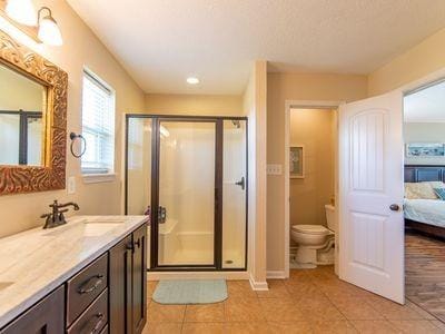 full bath featuring ensuite bathroom, a sink, toilet, and a shower stall