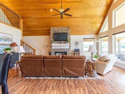 living area with wooden ceiling, high vaulted ceiling, wood finished floors, and a stone fireplace