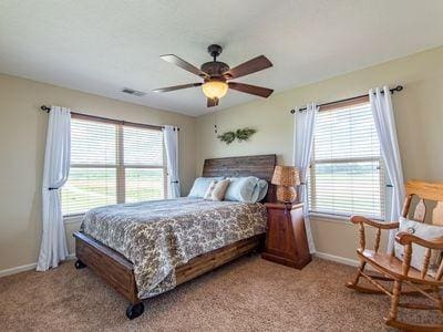 bedroom with visible vents, ceiling fan, light carpet, and baseboards