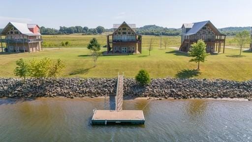 view of dock with a lawn and a water view