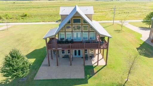 back of property with a rural view and a yard