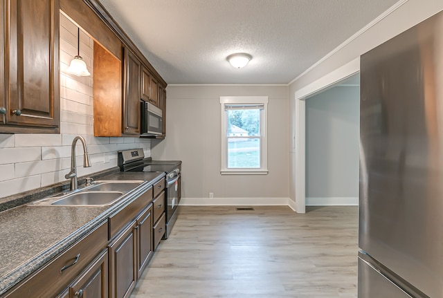 kitchen with decorative light fixtures, appliances with stainless steel finishes, light hardwood / wood-style flooring, tasteful backsplash, and a textured ceiling