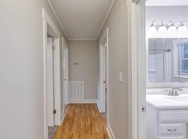 corridor with light hardwood / wood-style floors, sink, and crown molding