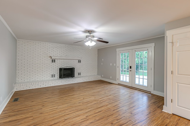 unfurnished living room with light hardwood / wood-style floors, crown molding, and brick wall