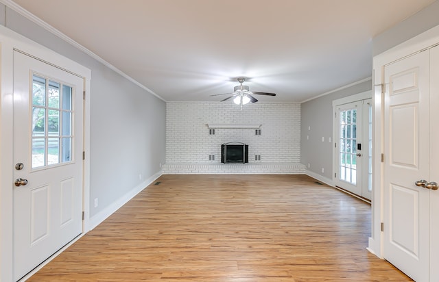 unfurnished living room with ornamental molding, a fireplace, light hardwood / wood-style floors, ceiling fan, and brick wall