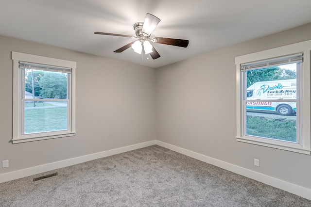 carpeted spare room featuring ceiling fan and a wealth of natural light