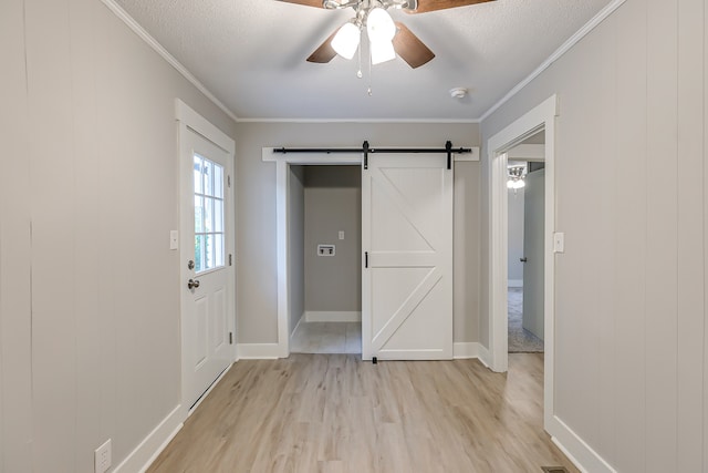 interior space with ceiling fan, light hardwood / wood-style floors, crown molding, and a barn door