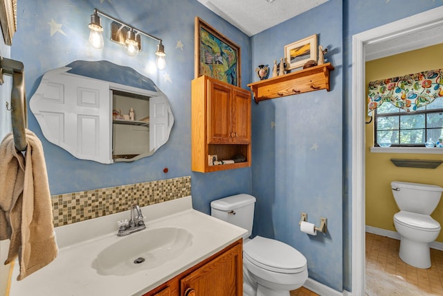 bathroom with tile patterned flooring, a textured ceiling, vanity, and toilet