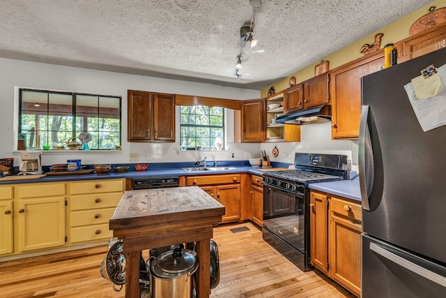 kitchen with black range with gas stovetop, dishwashing machine, light wood-type flooring, a textured ceiling, and fridge