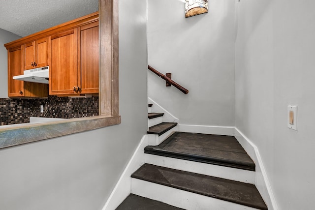 stairway featuring a textured ceiling